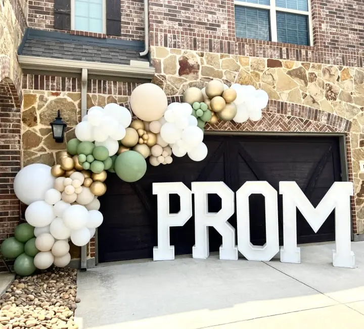 a sign that says prom in front of a brick building with balloons in the shape of the word prom