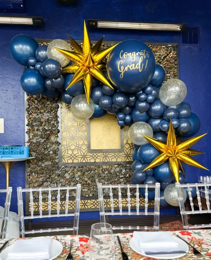 a table set up for a graduation party with balloons and star decorations on the front of the table and on the back of the table