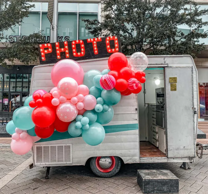 a mobile photo booth with balloons and a sign that reads photo booth on the front of the truck and the back of the truck