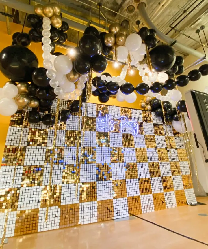 black and white balloons hanging from the ceiling of a room filled with gold and white tiles and black and white balloons