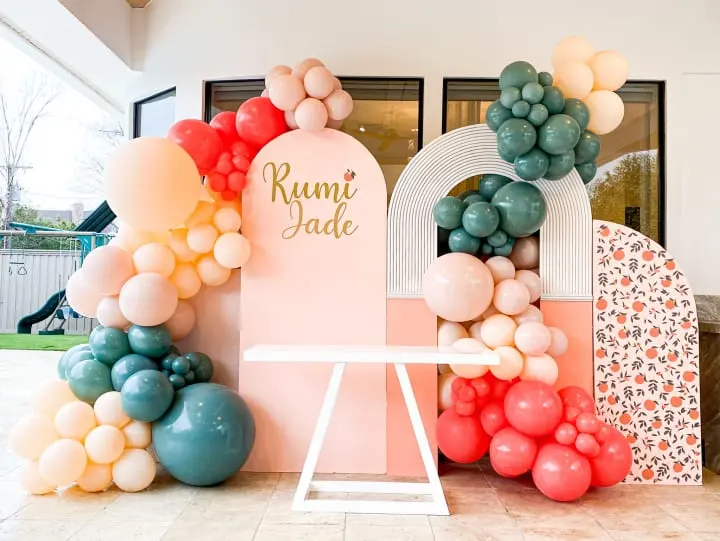 a bunch of balloons that are in front of a sign and a table with a laptop on it and a table with a laptop on it