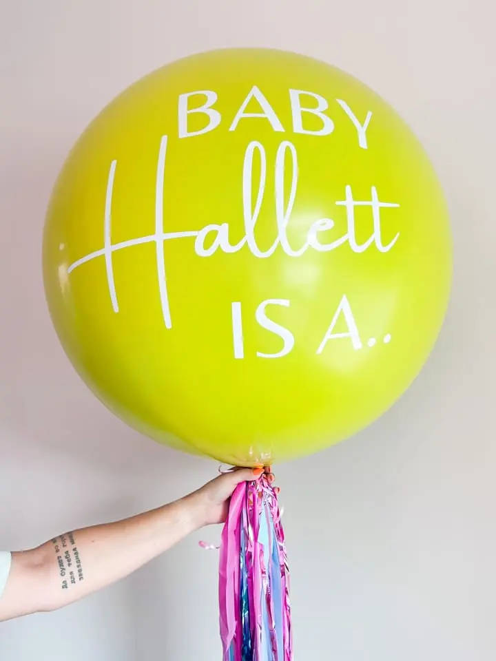 a person holding a yellow balloon with the words baby hallett is a written on the bottom of it