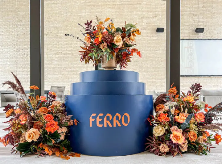 a large blue vase with flowers on top of it on a table in front of a window with a sign that reads ferro