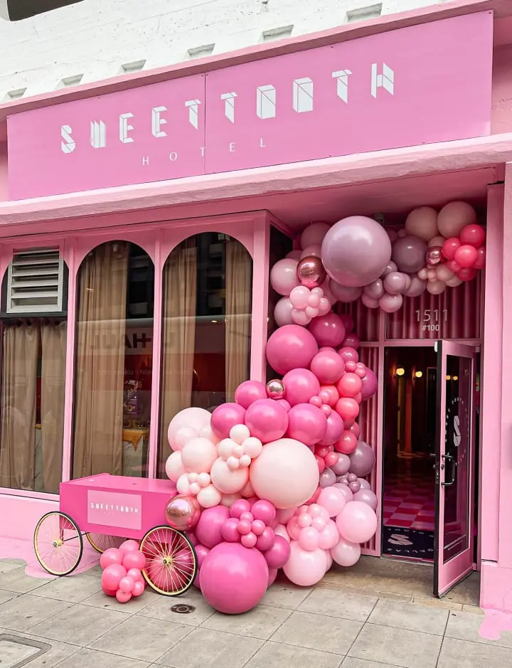 a pink storefront with balloons and a pink bike parked in front of the front of the store and a pink bike parked in front of the front of the store